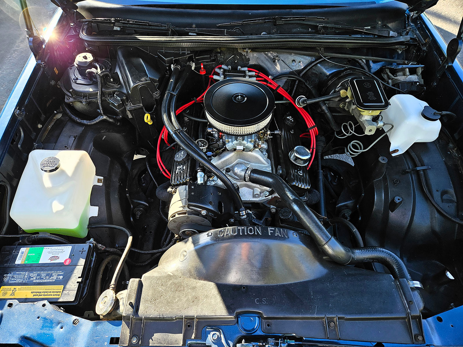 Under the hood of a 1986 Chevrolet El Camino Conquista featuring 350 ZZ4 engine swap. Mostly black color scheme with red spark plug wires.