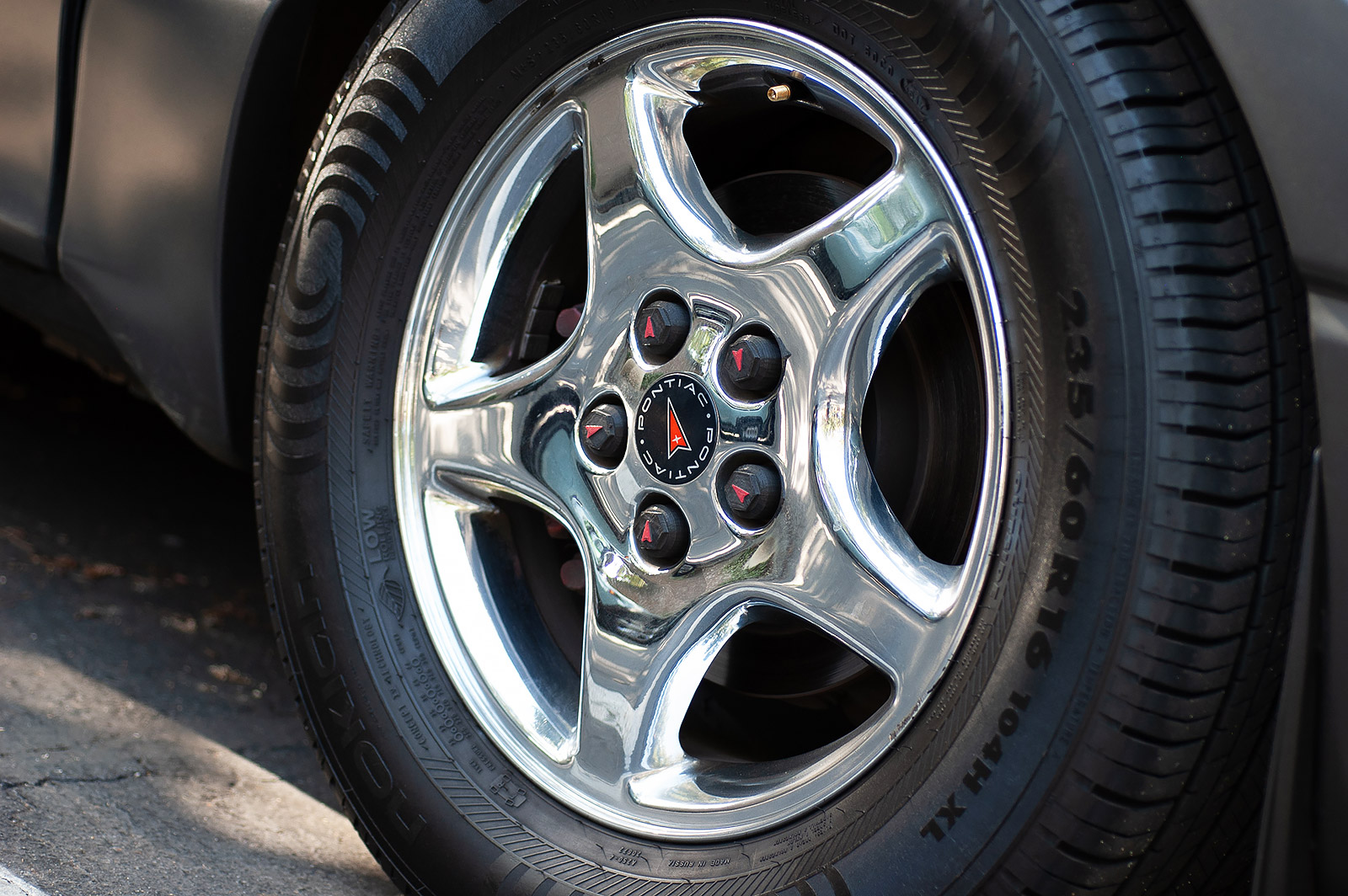 2003 AWD Pontiac Montana Thunder closeup of a custom chrome wheel and 3D printed custom Pontiac lug nut covers.
